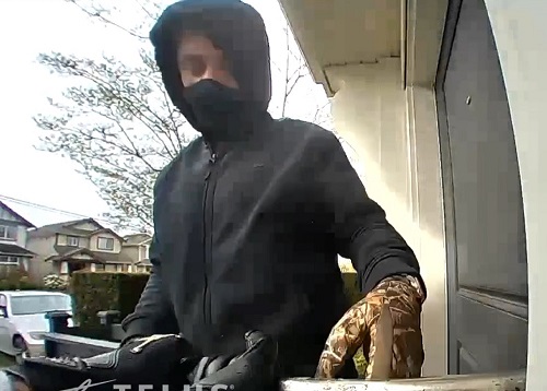Photo of suspect wearing black hoodie and black face mask with camouflage glove visible