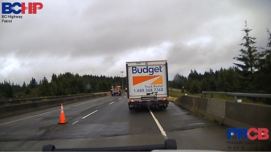 A rental truck stopped on the highway with a construction zone in the background