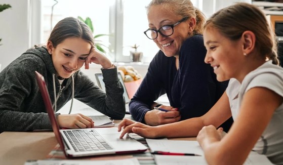 Une mère et ses deux filles regardent l’écran d’un ordinateur portatif.