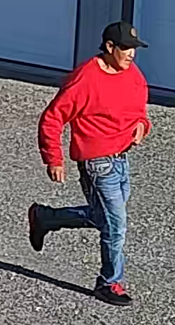 Photo of the first suspect wearing a long-sleeved red sweatshirt, black ball cap and blue jeans.