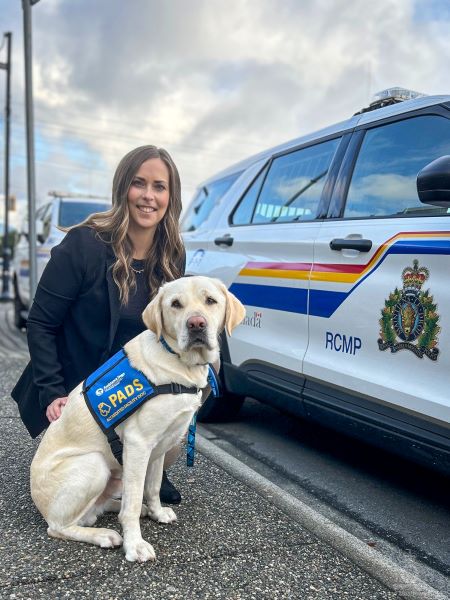 Loki  and handler Alysen Cox in front of a police car