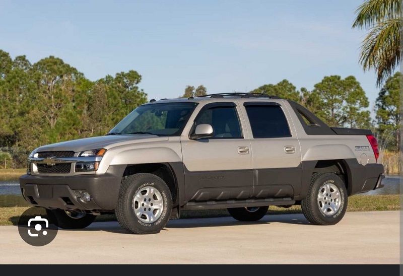 Photo of a 2004 Grey Chevrolet Avalanche truck. The truck has a black lower panel running along the side of it.