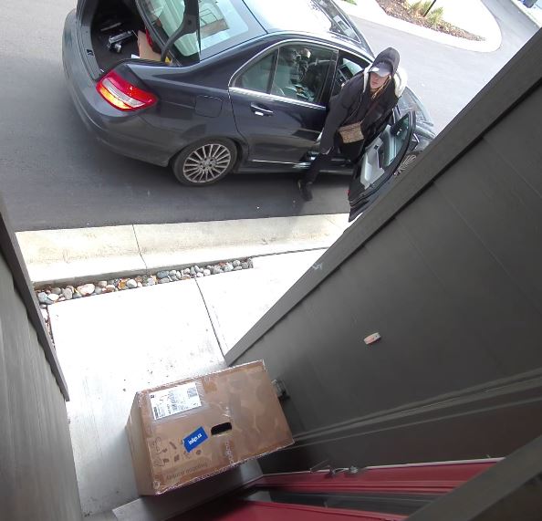 Woman exiting a vehicle just before she steels a package from a porch