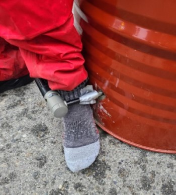 A person's ankle inside a bike lock attached to a barrel