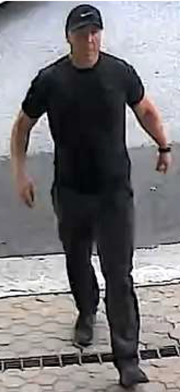Photo de face d’un homme portant un chapeau noir, un tee-shirt noir, un pantalon noir et des chaussures noires.