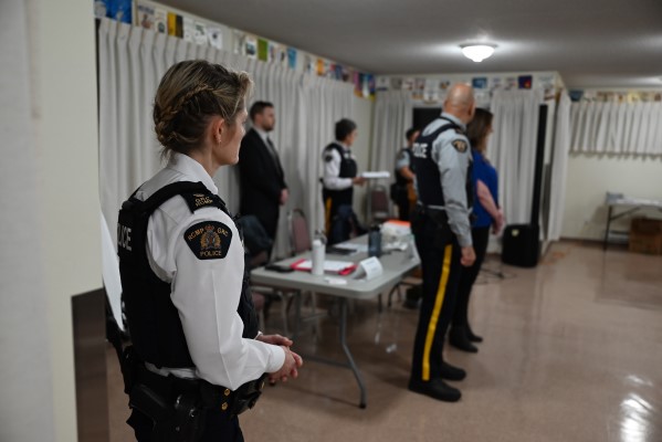 Insp. Peri Mainwaring stands in a community room with a table and several RCMP officers in uniform 