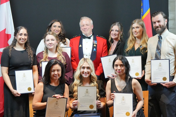 Group photo of Victim Services Unit after receiving an award from the Officer in Charge of the Burnaby RCMP detachment.  Everyone is in dress/formal outfits, smiling.