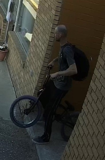 Man walking his BMX Bike wearing a black back pack