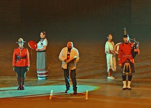 Des membres de la GRC vêtus de la tunique rouge se tiennent debout en compagnie d’artistes des Premières Nations. 