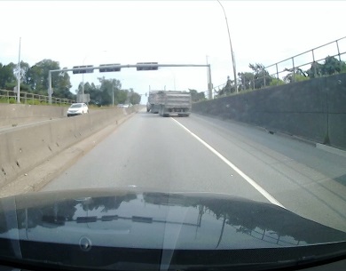 Rear view of dump truck crossing over solid line from right to left