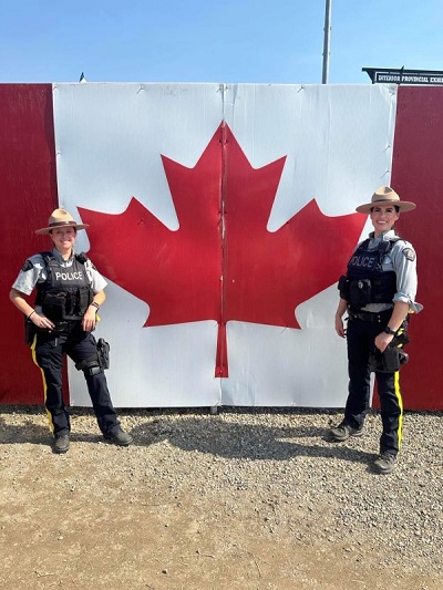 Des agentes de la GRC posent devant un drapeau canadien à l’Exposition provinciale intérieure de 2023.
