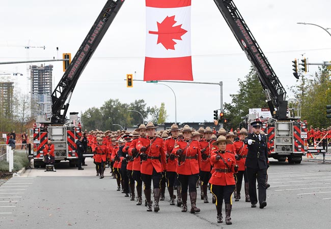 Members marching in red serge under Canada flag