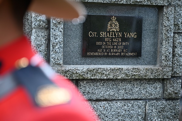 Cst. Shaelyn Yang’s name on a black plaque on a stone cairn beside an RCMP officer wearing Red Serge