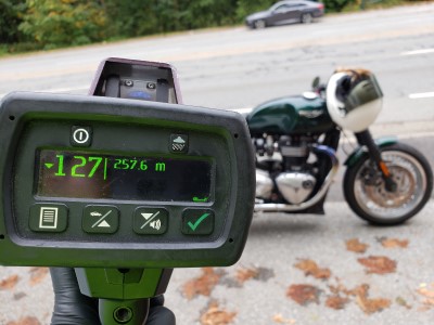 Speed gun with the number 127 on it and a motorcycle in the background.