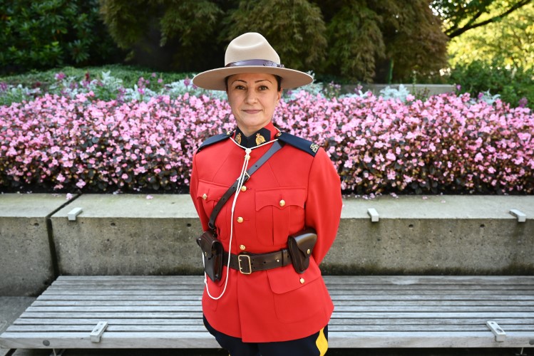 Cst. Sahar Manochehri wearing a Red Serge outdoors beside pink flowers